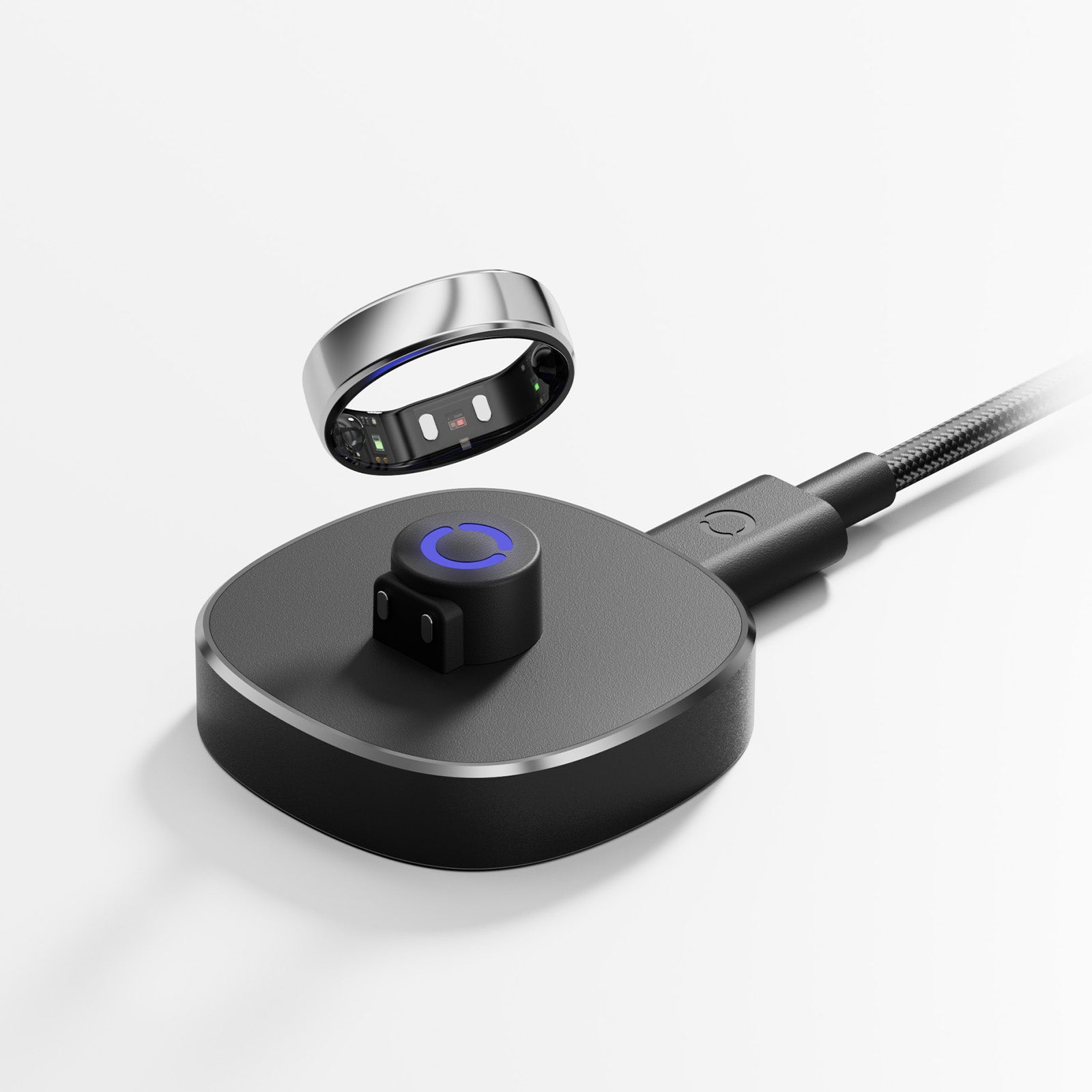 Black smart ring charging dock with silver trim, blue indicator light, magnetic charging for sleep tracking.